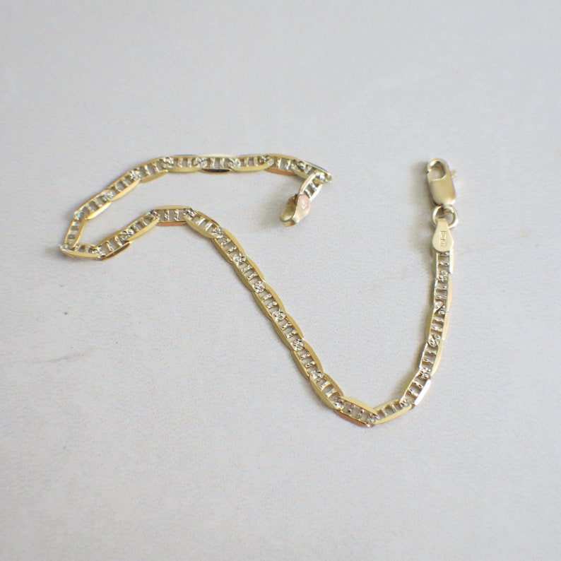 May include: A gold chain bracelet with a delicate, linked design. The chain is accented with small, clear stones.