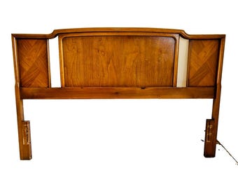 May include: A wooden headboard with a geometric pattern on the side panels. The headboard is a light brown color and has a curved top.