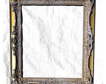 May include: A gold ornate picture frame with a heavily carved design. The frame is empty and ready to hold a picture or artwork.