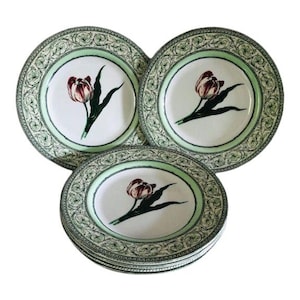 May include: Set of six green and white porcelain plates with a floral design featuring a tulip. The plates have a decorative border with a green and white pattern.