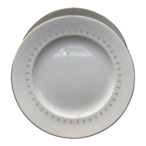 May include: A white ceramic dinner plate with a gold rim and a delicate gold floral pattern around the edge.