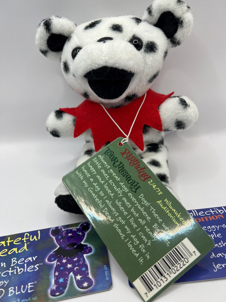 May include: A black and white dalmatian plush bear wearing a red collar. The bear is holding a tag that reads "Birthday Tour Memory 2/4/78 Milwaukee Auditorium Dogs! There were always great dogs everywhere. Big ones, little ones, scruffy ones but all really happy and loved. Where I live I can't have a dog so I always got my dog fix in with my Grateful Dead shows, I loved it."