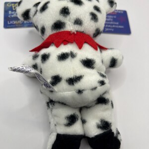 May include: A black and white dalmatian plush toy with a red collar. The toy is standing on a white surface.