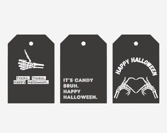 May include: Three black and white Halloween gift tags with skeleton hand designs. The first tag says "Tricks. Treats. Happy Halloween." The second tag says "It's Candy Bruh. Happy Halloween." The third tag says "Happy Halloween" with a skeleton hand making a heart shape.