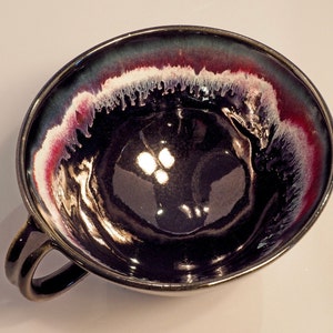 May include: A black ceramic bowl with a white and red rim. The bowl has a glossy finish and a unique, hand-painted design.