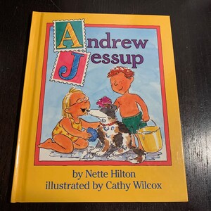 May include: A yellow book cover with the title "Andrew Jessup" and the author "by Nette Hilton illustrated by Cathy Wilcox". The cover features a cartoon illustration of two children and a dog.
