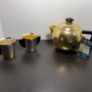May include: Gold ColorTone 8-cup instant coffee and tea maker with two matching gold cups with black handles. The tea maker is made of alumi-lite aluminum.