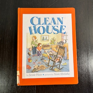 May include: An orange book titled "Clean House" with illustrations of a messy living room. The book is by Jessie Haas and illustrated by Yossi Abolafia.