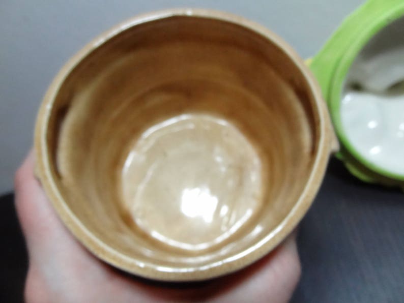 May include: A close-up of the inside of a ceramic jar with a brown glaze. The jar is empty and has a smooth, rounded interior.