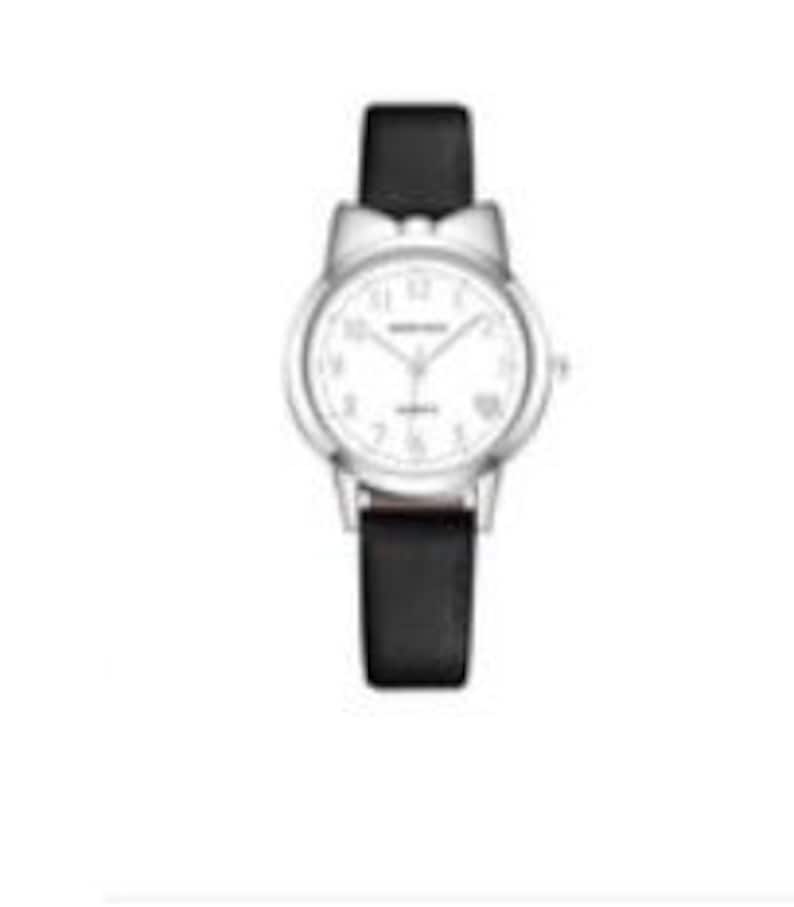 May include: A silver-toned wristwatch with a white face and black leather band. The watch features a bow-shaped bezel and a date display. The band measures approximately 0.75 inches wide. The watch hands point to 10:09.