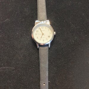 May include: A silver-toned analog watch with a white face and black leather band. The watch face features black numerals and hands, with the brand name "Kurio" at the top. The band is approximately 0.5 inches wide.