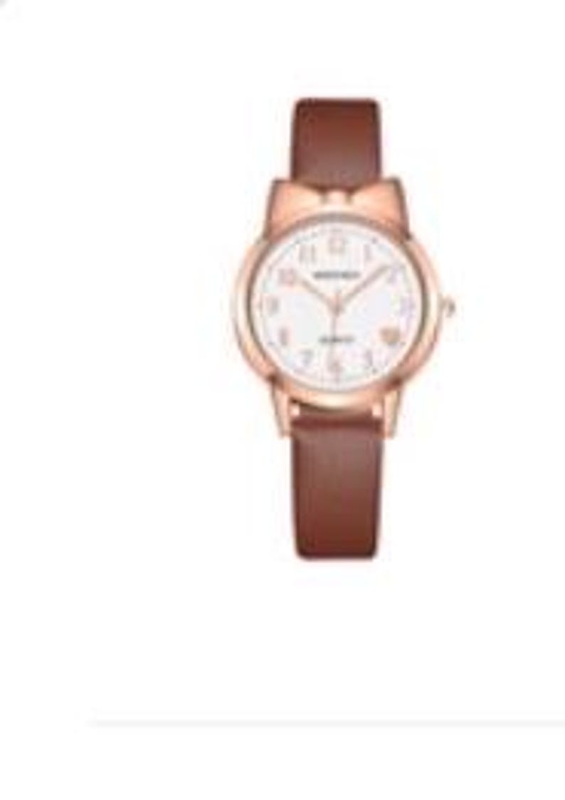 May include: A rose gold wristwatch with a white face and brown leather band. The watch features a bow-shaped design at the top of the watch face. The watch has a round face with gold-colored hands and hour markers. The band is approximately 0.75 inches wide.