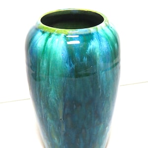 May include: A tall, ceramic vase with a green and blue marbled glaze. The vase has a rounded bottom and a wide opening at the top.