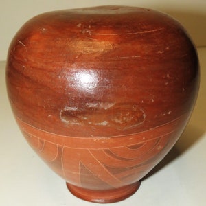 May include: A terracotta pottery vase with a geometric design in a lighter shade of terracotta. The vase is round with a slightly wider base and a narrow neck.