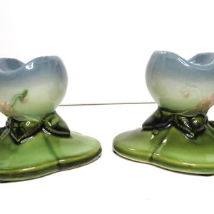 Könnte beinhalten: Ein Paar antike Kerzenhalter aus Keramik in Form einer Blume mit grünem Sockel und einem blauen und weißen Blumendesign.