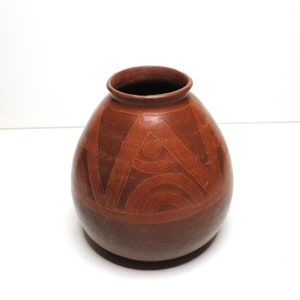 May include: A brown ceramic vase with a geometric design. The vase has a rounded body and a narrow opening.