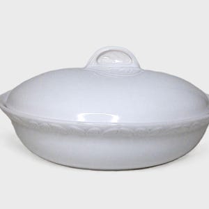 Puede incluir: Fuente de cer&aacute;mica blanca con tapa. La fuente tiene forma redondeada con un borde decorativo y un asa en la tapa. La fuente para servir est&aacute; dise&ntilde;ada para alimentos.