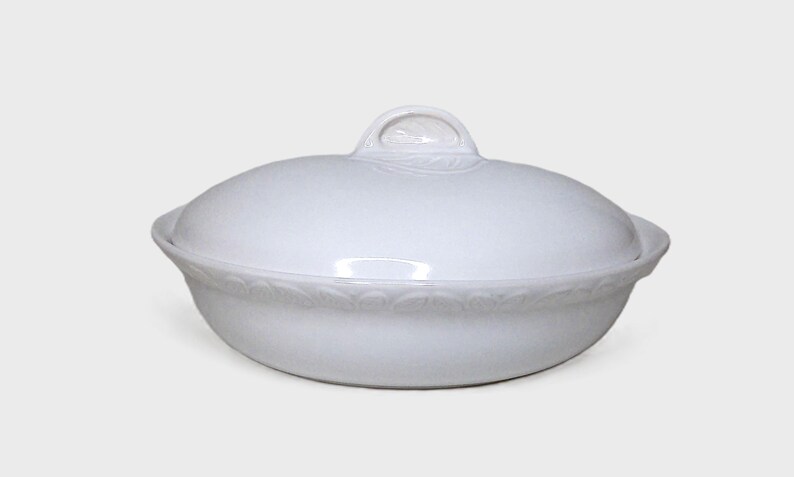 Puede incluir: Fuente de cer&aacute;mica blanca con tapa. La fuente tiene forma redondeada con un borde decorativo y un asa en la tapa. La fuente para servir est&aacute; dise&ntilde;ada para alimentos.