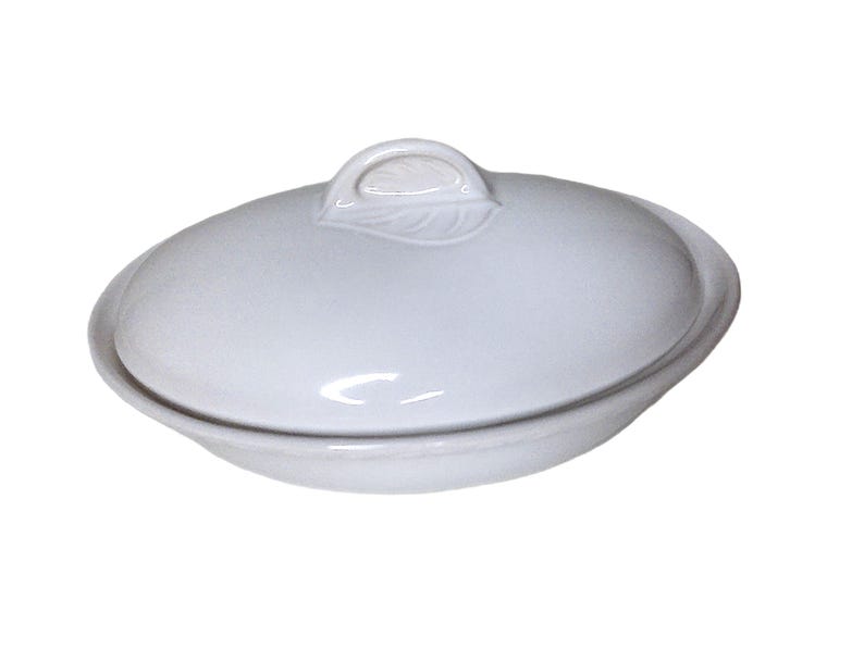 Puede incluir: Fuente ovalada de cer&aacute;mica blanca con tapa. La tapa tiene un asa en forma de hoja. La fuente est&aacute; dise&ntilde;ada con una est&eacute;tica sencilla y elegante. La fuente es adecuada para servir alimentos.