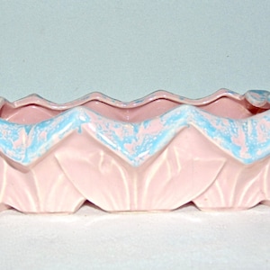 May include: A pink ceramic planter with a blue glaze. The planter is shaped like a series of overlapping leaves.