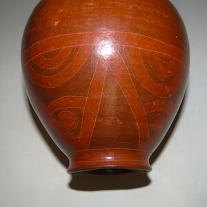 May include: A brown ceramic vase with a geometric design. The vase has a rounded body and a narrow neck.