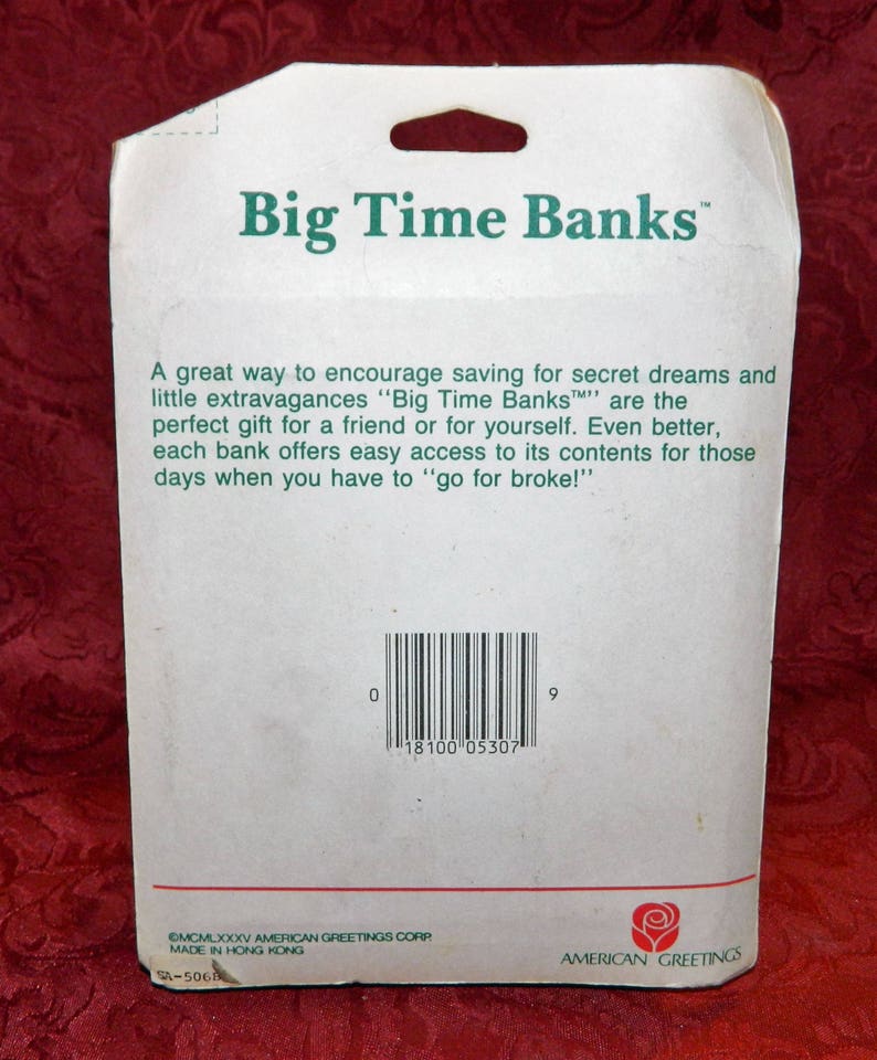 May include: White cardboard packaging for "Big Time Banks" with green text. The text includes the brand name and a description of the product. A barcode and the American Greetings logo are also visible.