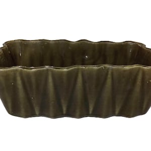 Pode incluir: Um prato retangular de cerâmica verde-oliva com borda ondulada. As laterais do prato apresentam um design texturizado e canelado. Esta peça decorativa é adequada para servir ou expor.