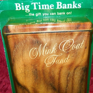 May include: A rectangular bank with a mink coat design. The bank has the words "Mink Coat Fund" in elegant script. The top of the bank is visible, with the words "Big Time Banks" and "...the gift you can bank on!" printed on the green packaging.