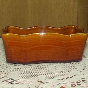 以下が含まれることがあります： 波打つ縁のある茶色の陶器製のプランター。プランターは釉薬がかけられており、素朴な外観をしています。