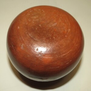 May include: A round, terracotta-colored pottery bowl with a smooth, slightly textured surface. The bowl is unglazed and has a natural, earthy tone.