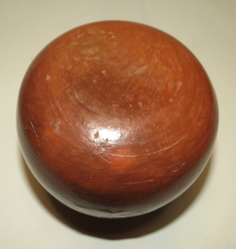 May include: A round, terracotta-colored pottery bowl with a smooth, slightly textured surface. The bowl is unglazed and has a natural, earthy tone.
