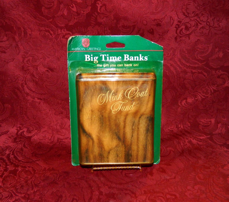 May include: A rectangular money bank with a faux mink coat design. The bank is in a green and clear plastic package. The text "Big Time Banks" and "Mink Coat Fund" are visible on the bank.