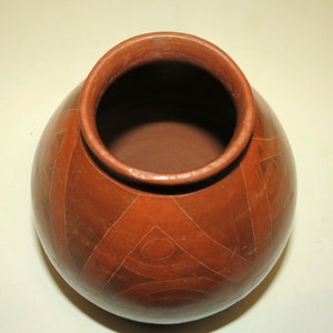 May include: A terracotta pot with a geometric design. The pot is brown and has a wide mouth.