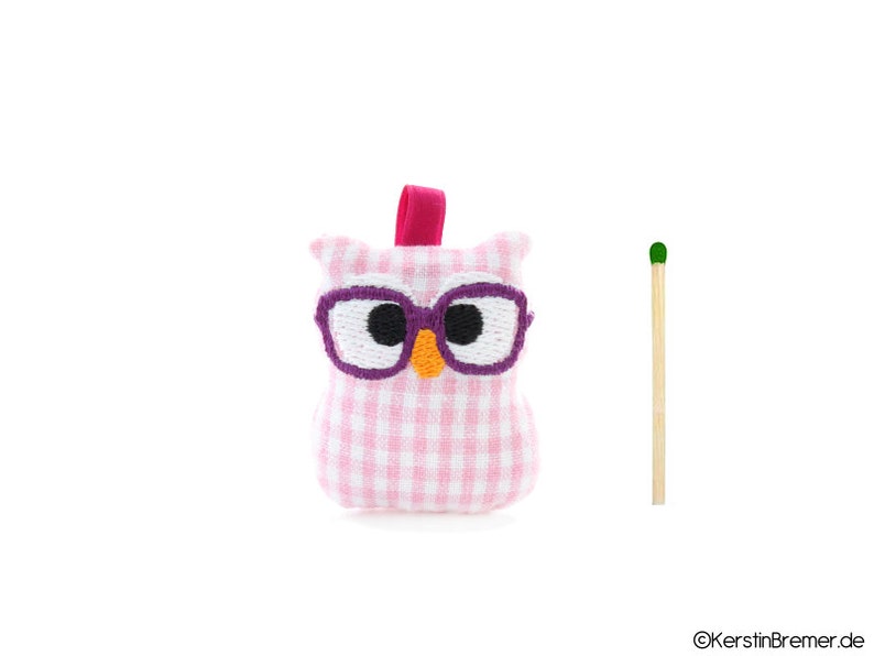 Puede incluir: Juguete de peluche de b&uacute;ho de guinga rosa y blanco con gafas moradas y pico naranja.