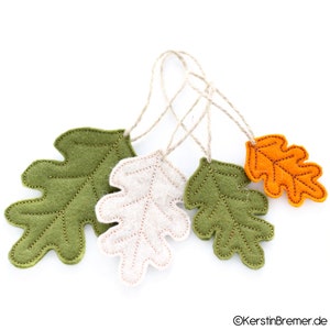May include: Four felt oak leaves in green, cream, and orange with gold stitching. Each leaf has a twine loop for hanging.
