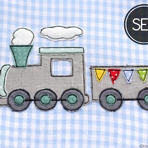 May include: A grey fabric train with a green smoke stack and a blue and white cloud. The train has a flatbed car with colourful flags. The text "SET" is in a black circle.