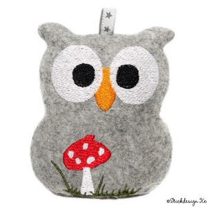 May include: A gray felt owl with embroidered eyes, orange beak, and a red and white mushroom with green grass.