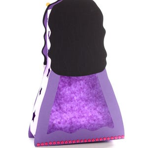 May include: Purple papercraft princess with a black hair crown and a sparkly purple dress. The dress has a white star pattern and a pink trim.