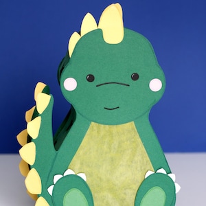 Die gebastelte Stegosaurus Dinosaurier Laterne präsentiert vor einem blauen Hintergrund. Digitales Bastelset inklusive PDF-Vorlage und SVG DXF Plotterdatei