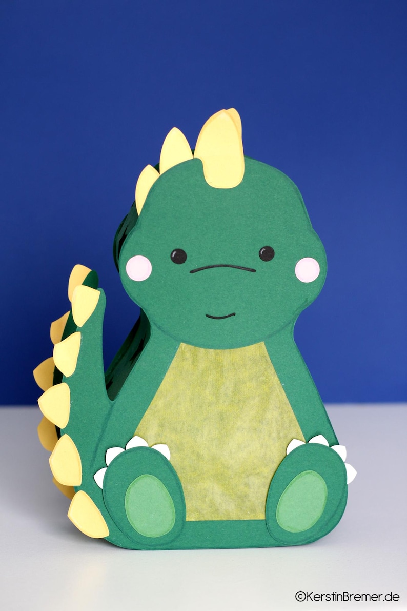 Die gebastelte Stegosaurus Dinosaurier Laterne präsentiert vor einem blauen Hintergrund. Digitales Bastelset inklusive PDF-Vorlage und SVG DXF Plotterdatei