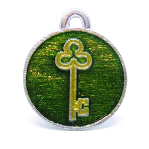 May include: A silver charm with a green enamel background and a gold key with a clover design.