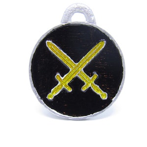 May include: A silver charm with a black enamel background and two crossed swords in yellow enamel.