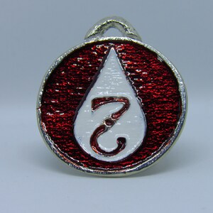 May include: A red and white enamel pin shaped like a blood drop with the number 7 inside. The pin has a silver metal loop on the top.