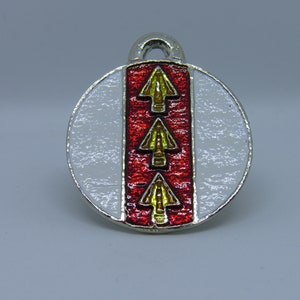 May include: A silver charm with a red and white enamel design. The charm features three gold arrows pointing upwards.