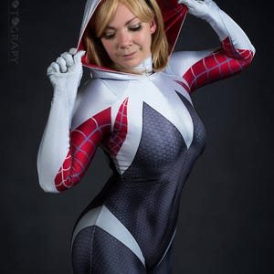 May include: A full-body cosplay costume in white, black, and red, featuring a hood and gloves. The suit has a spiderweb design on the arms and a honeycomb pattern on the torso. The number "2" is visible in the top right corner.