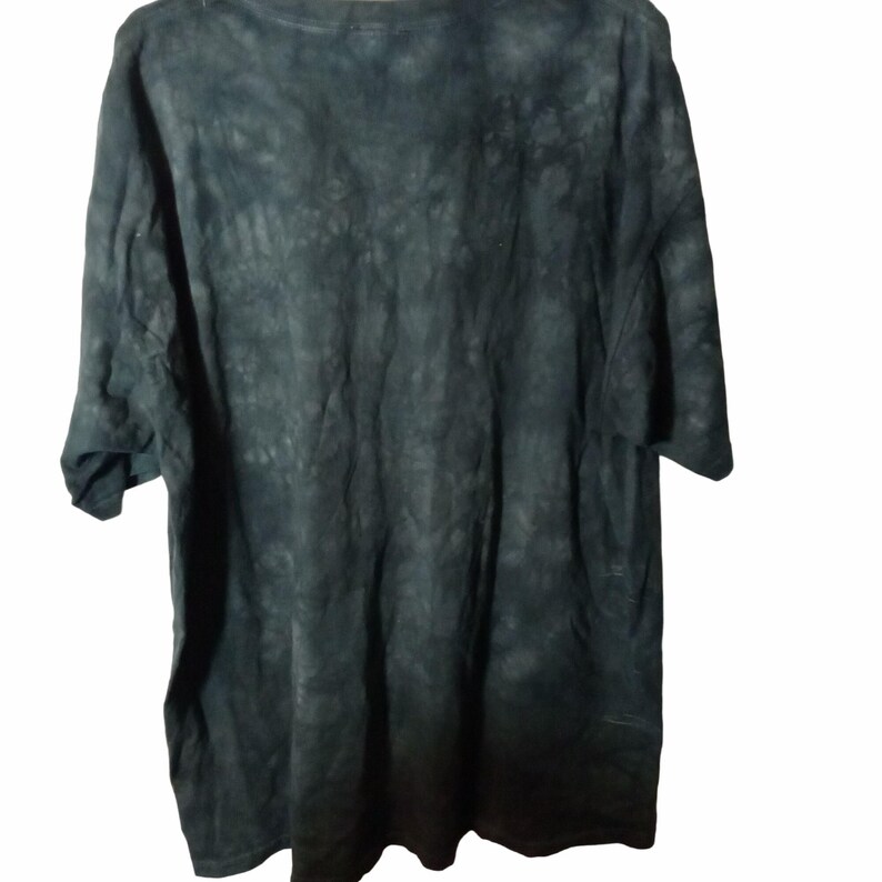 May include: Dark green tie-dye t-shirt. The shirt has short sleeves and a crew neck. The fabric has a mottled appearance with shades of dark green and black. The shirt is made of a soft, comfortable material.