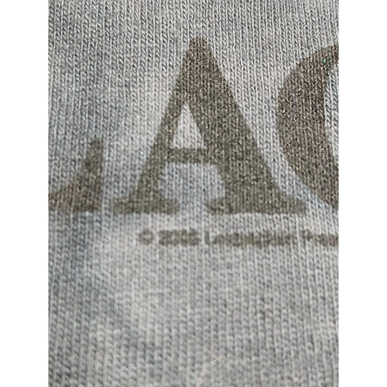 May include: Close-up of a gray fabric with the letters "A" and "C" printed in a darker gray. The text "&copy; 2006" is visible below the letters. The fabric has a textured appearance.