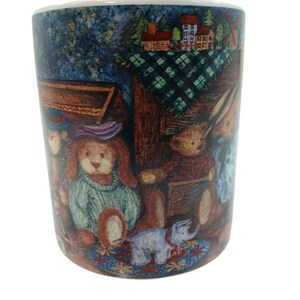 May include: A ceramic mug featuring a colorful illustration of anthropomorphic animals, including a rabbit in a green sweater and a bear in a red shirt, set against a backdrop of a small village with houses, trees, and a green checkered tablecloth.