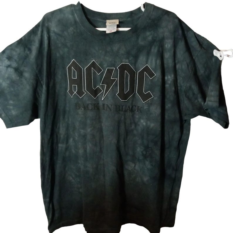 May include: Dark green tie-dye t-shirt featuring the band AC/DC's logo in white, with the text "BACK IN BLACK" below. The shirt has short sleeves and a crew neck.