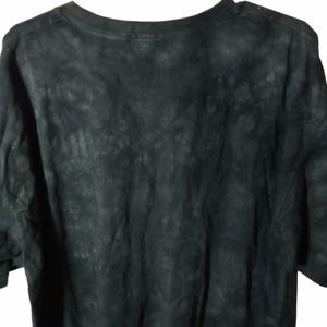 May include: A black t-shirt with a tie-dye pattern. The shirt has a crew neck and short sleeves. The fabric appears soft and slightly faded, with a mottled, dark gray and black design.
